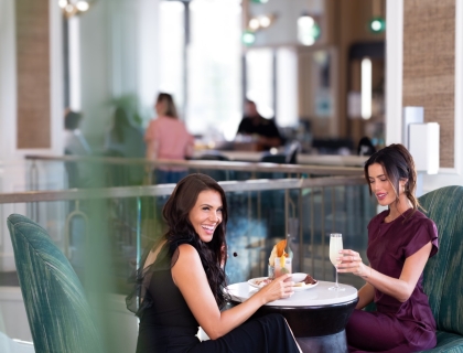 Two women engaged in conversation while sitting at a table, sharing a moment together.