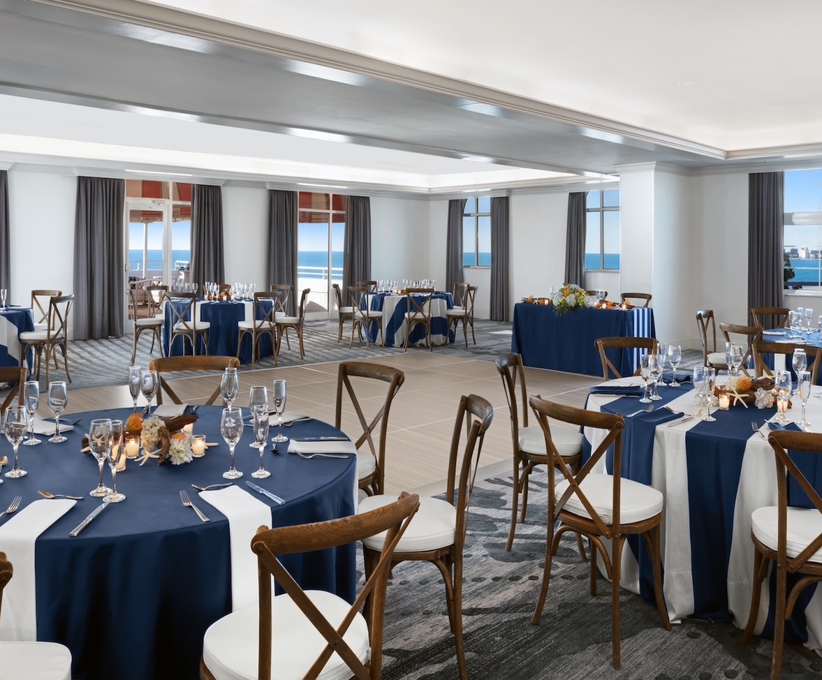 large meeting room with round tables and a view of the ocean